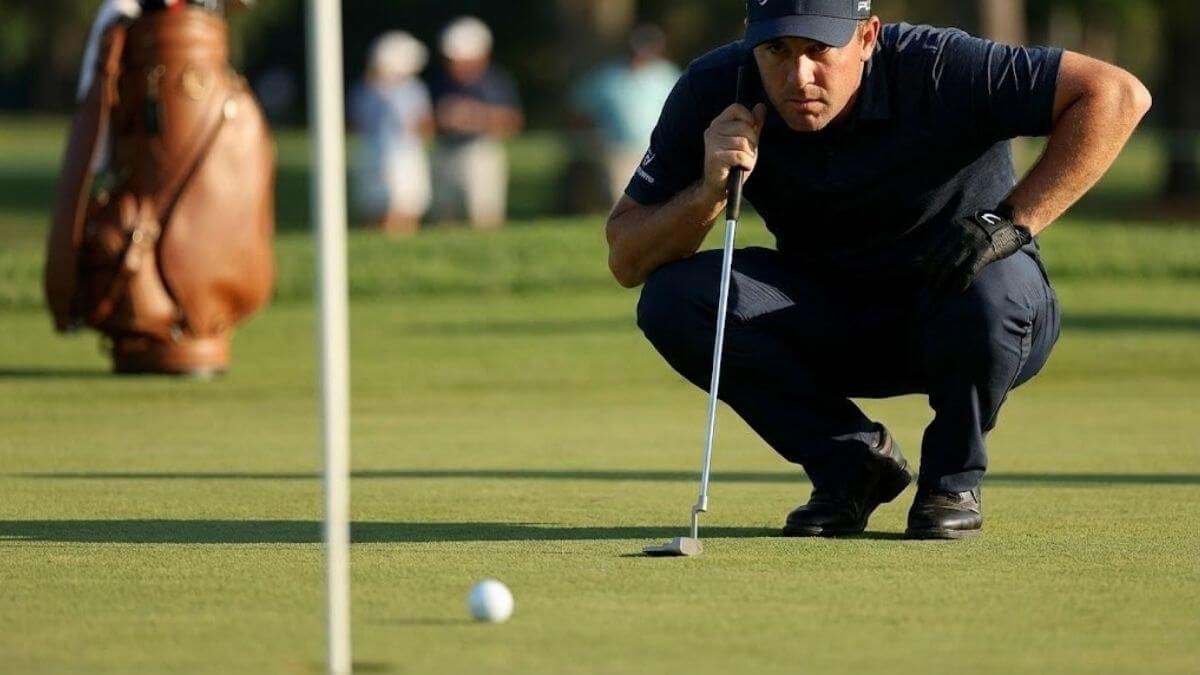 นักกอล์ฟกำลังโฟกัสกับการพัตต์ลูกกอล์ฟเพียงลูกเดียวบนกรีนซ้อม ด้วยสีหน้ามุ่งมั่น