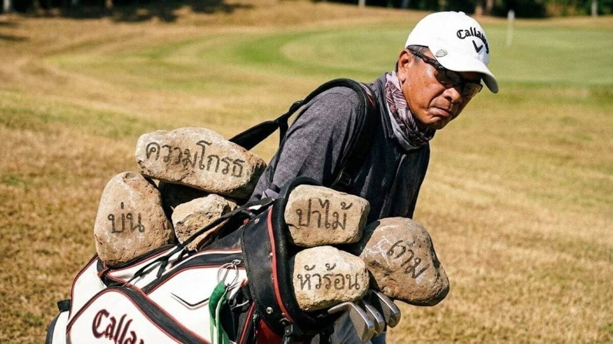 นักกอล์ฟแบกถุงกอล์ฟที่เต็มไปด้วยก้อนหินแห่งความโกรธ สื่อถึงการระบายอารมณ์ที่เป็นภาระ ไม่ใช่การปล่อยวาง